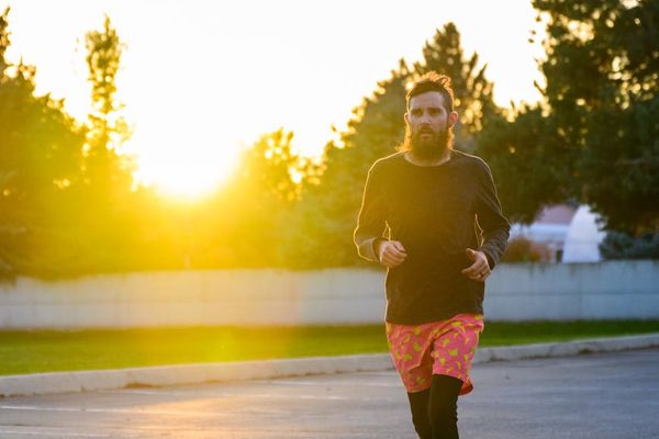 Person joyfully jogging in a park during sunrise.